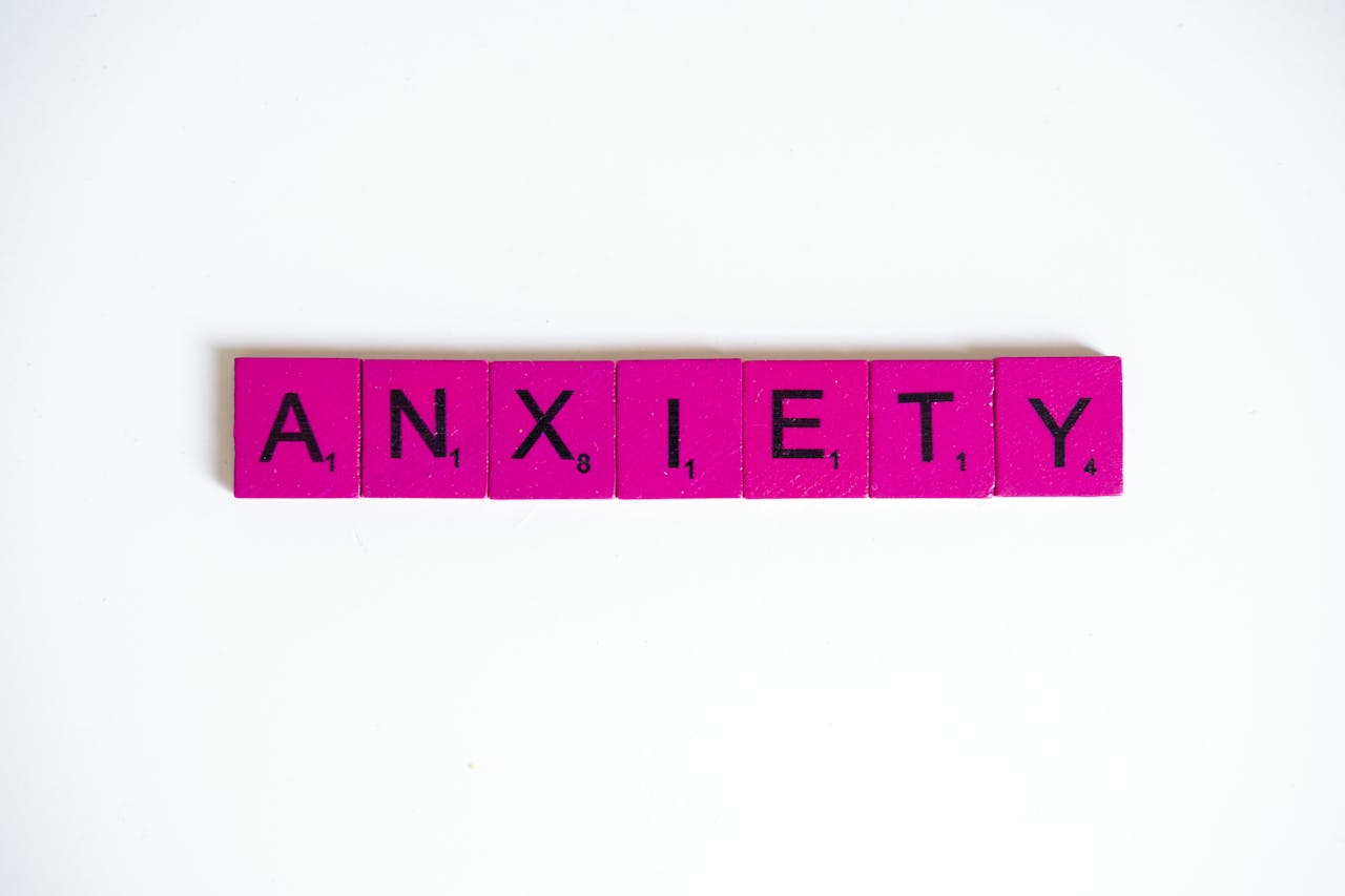 about-bg Pink Scrabble tiles spelling 'anxiety' on a white surface. Concept of mental health.
